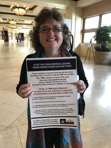 Program Director Shela Hemphill holds a 'Stop The Texas Medical Board From Persecuting Our Doctors' poster at the Truth About Cancer Symposium
