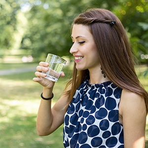 A woman drinking a glass of water. An effective weight loss tip is to drink 6-8 glasses of water daily.