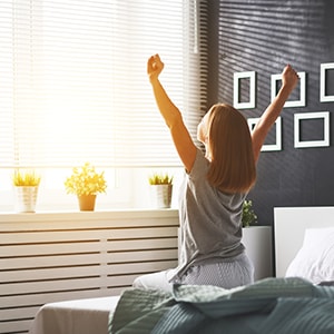 A woman waking up from a restful night's sleep. Adequate sleep is essential for heart health.